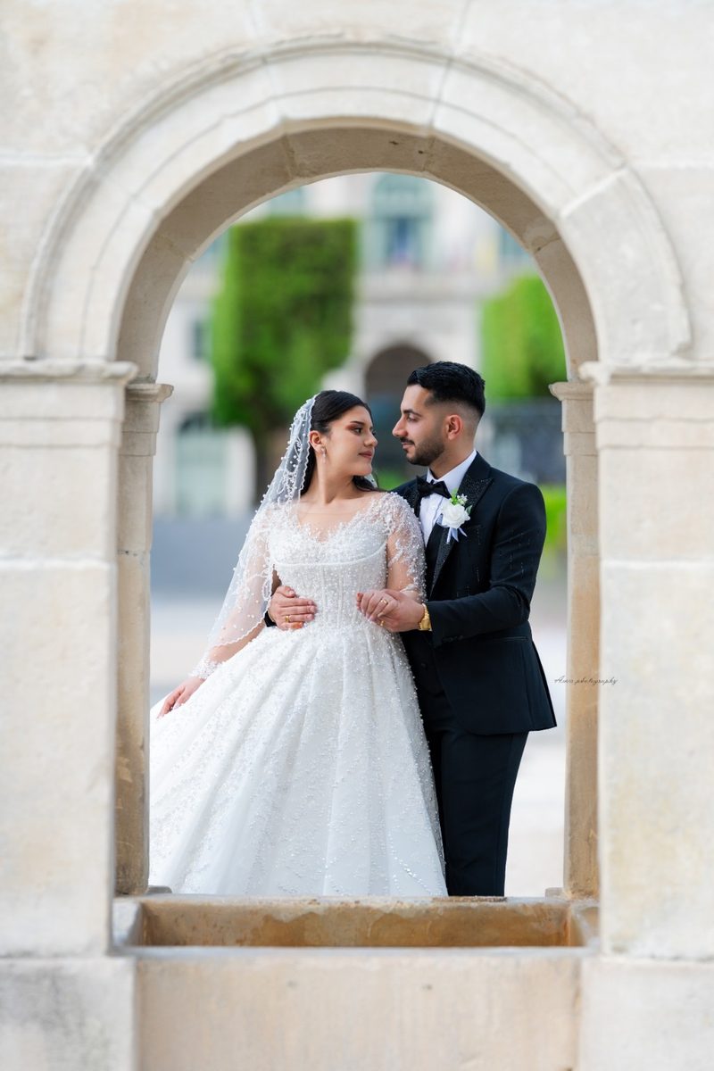 Couple de mariés sous une arche en pierre à Paris